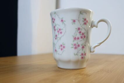 Biały kubek w drobne kwiatuszki  Bohemia Porcelán z minimalnie odbijającym się światłem słonecznym