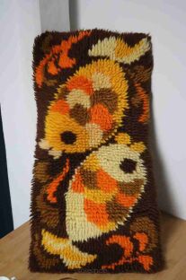 Kilim ryby z czasów PRL z motywami dwóch ryb na brązie luźno oparte o ścianę