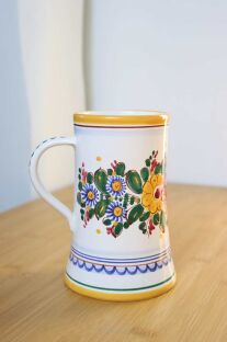 Kufel z wielobarwnymi kwiatami, żółtym rantem i białym uszkiem z zielonymi kropkami