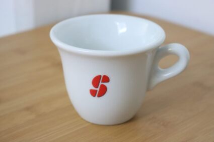 Większa filiżanka Esse Café  na Cappuccino z widocznymczerwonym logo z przodu