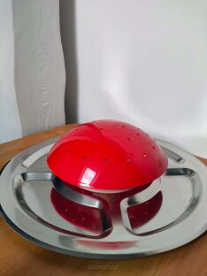 Czerwony grzybek ze srebrną paterą Party Pilz położony na blacie biurka