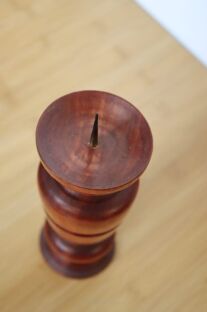 Ciemny świecznik toczony z igłą u góry na drewnianej powierzchni