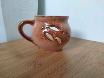 Świecznik w kształcie szklanki z uszkiem po lewej i widocznymi wyżłobieniami w kształcie liści