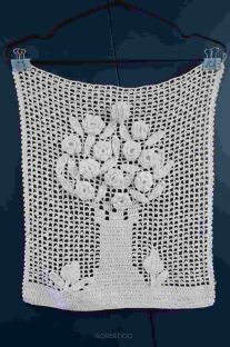 Biała makatka zrobiona na szydełku Kwiaty w wazonie na tle granatowej deski