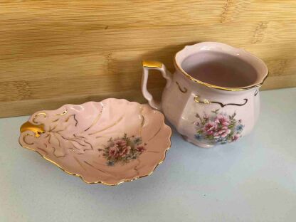 Kubek i miseczka różówy porcelán Chodov ze złotymi rantami i kwiatkami na tle deski